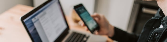 Una persona con un celular en la computadora