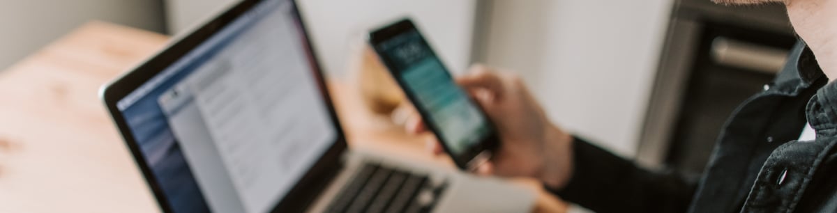 Una persona con un celular en la computadora